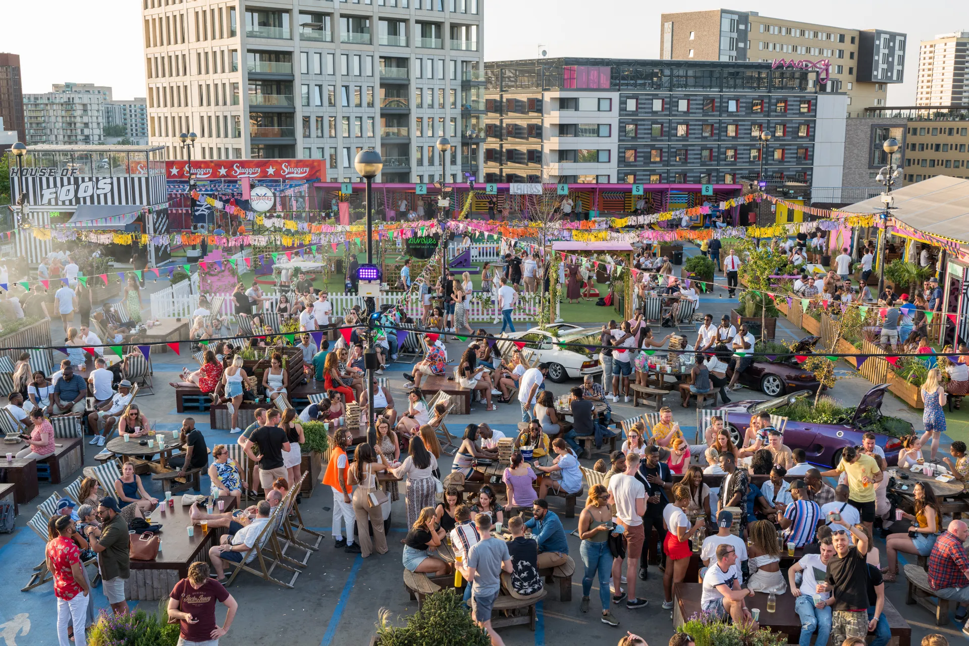 Photo of a crowded rooftop bar with tall building in the background