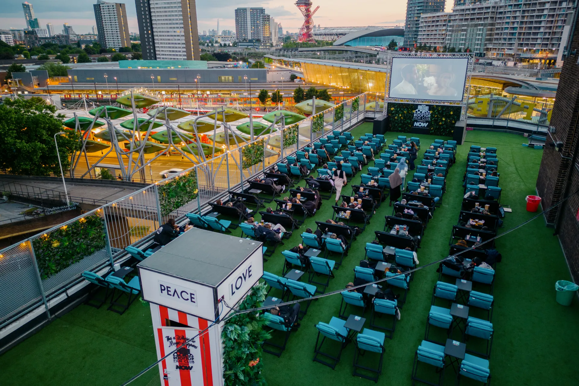 Deckchairs and cinema screen against buildings in the distance at dusk